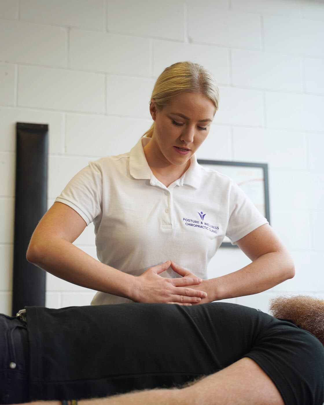 Bianca Downey adjusting a patient's lower back as they lie face down on the treatment table.