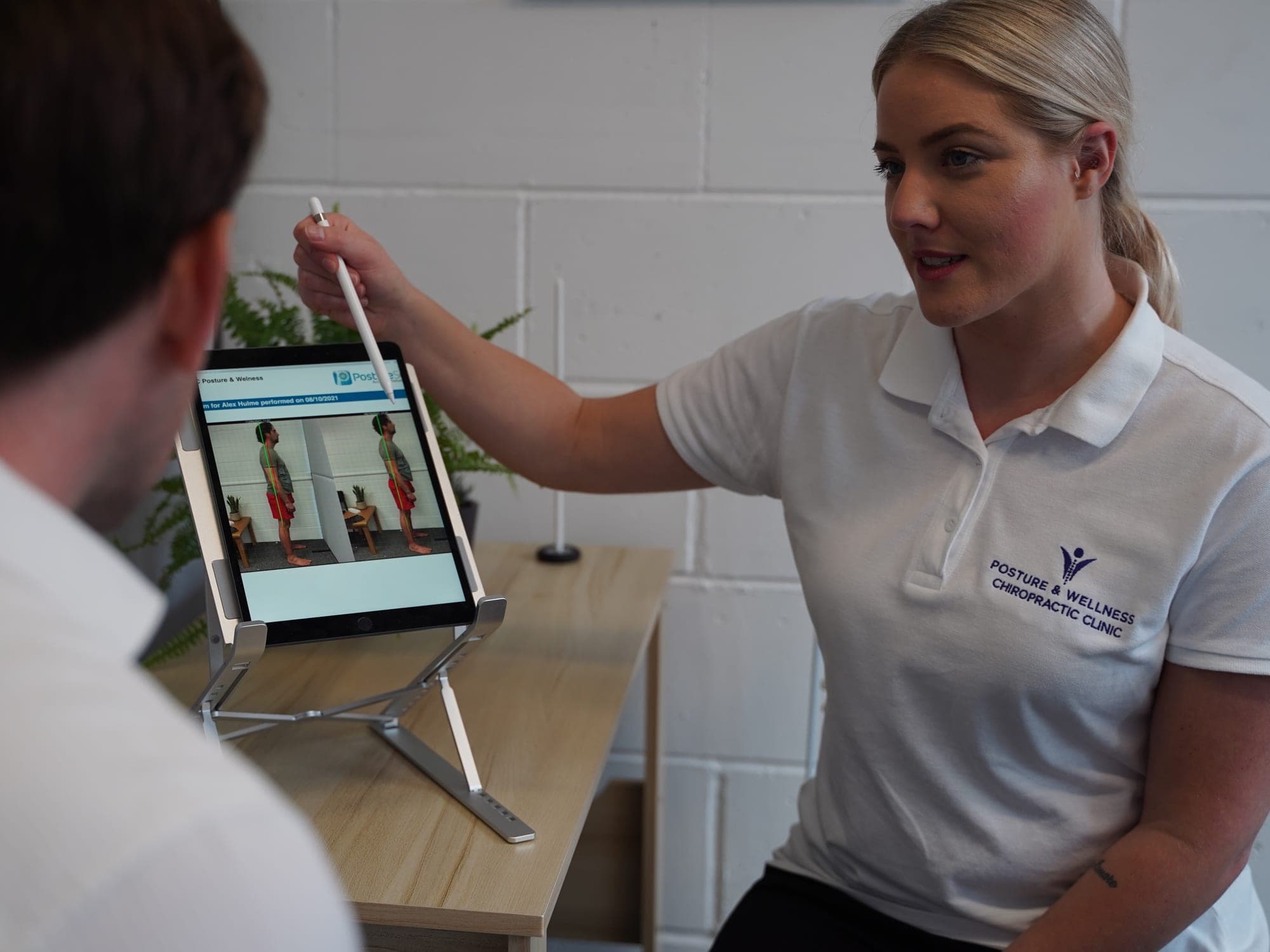 Bianca Downey talking a patient through his posture photographs on the tablet.