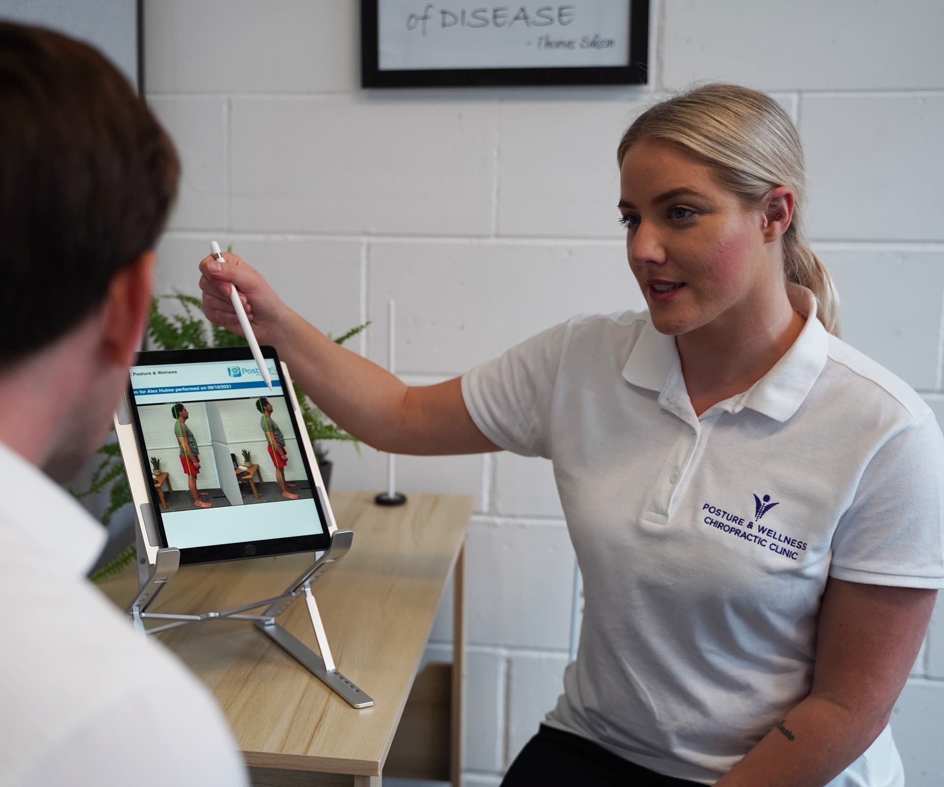 Bianca Downey talking a patient through his posture photographs on the clinic tablet.