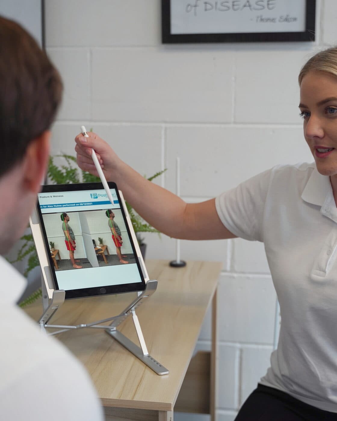 Bianca Downey pointing out a patient's postural photographs on the tablet.