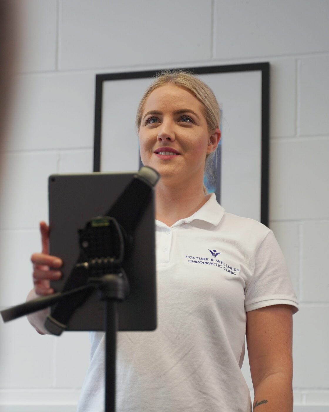 Bianca Downey behind the clinic tablet on its tripod, taking posture photographs.